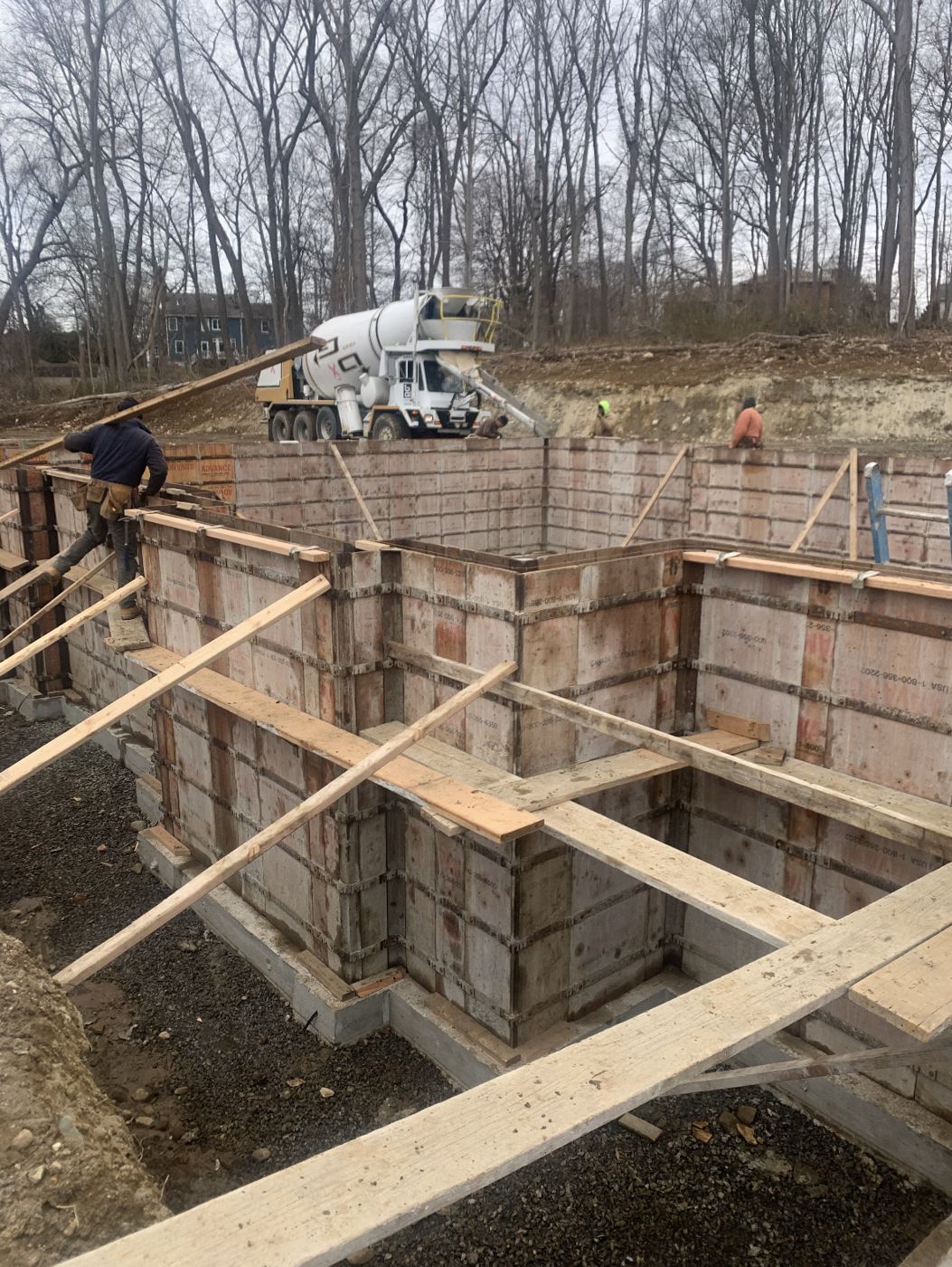 Braced wall forms on a house foundation with a mixer truck ready to pour