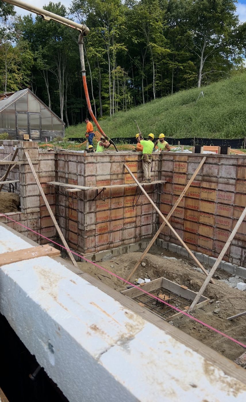 Crew on braced wall forms guiding a pump hose during a wall pour
