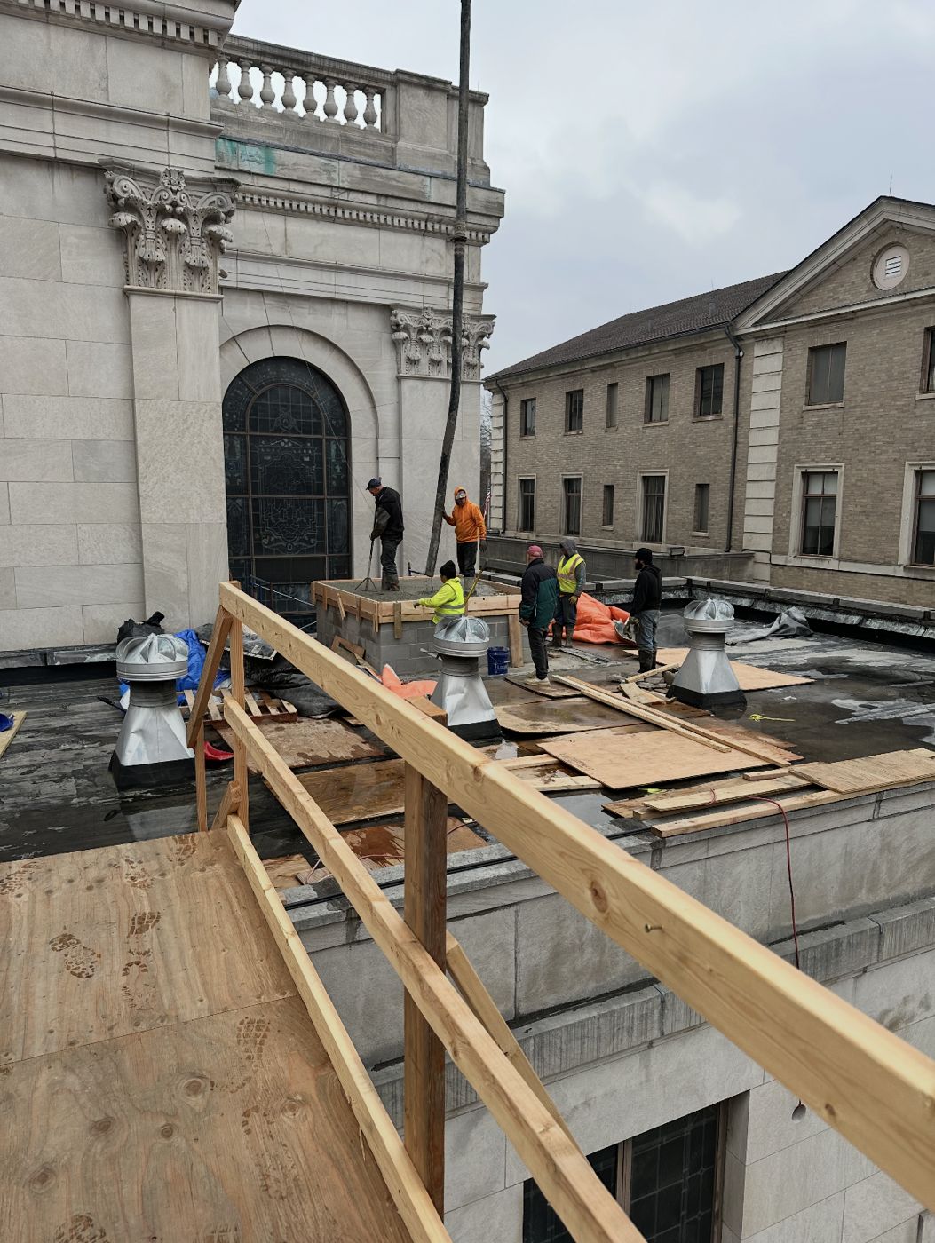 Crew pouring a formed pad on the roof of a stone building