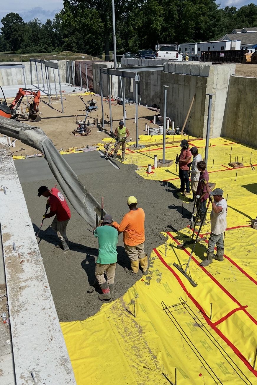 Crew placing a slab over a vapor barrier on a commercial site