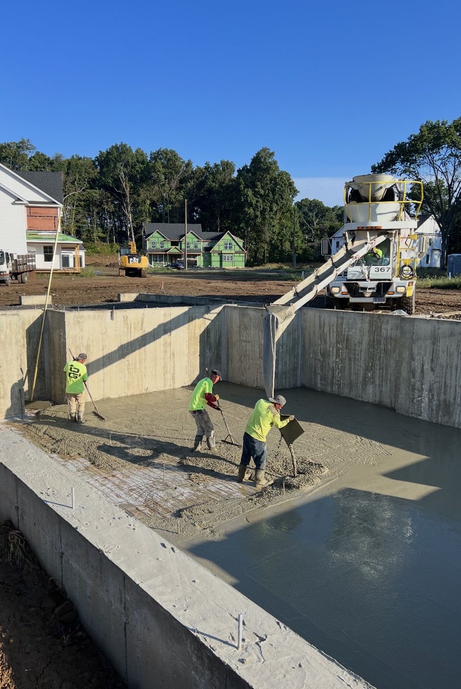 Crew pouring and raking a basement floor slab